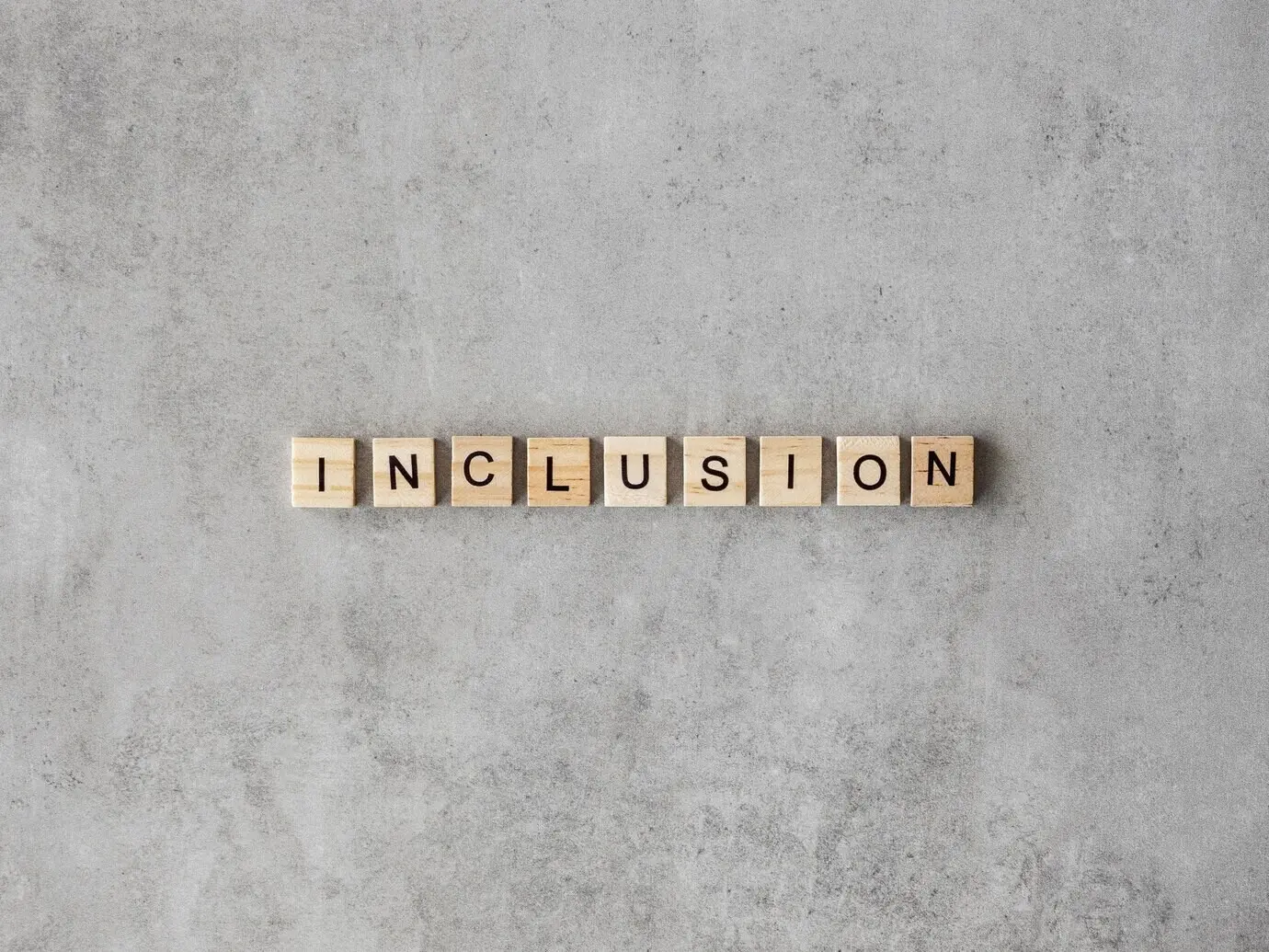 Слово «Inclusion», написанное буквами Скраббла на мраморном фоне.